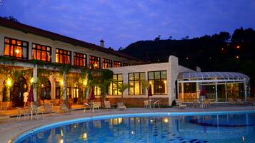 Una piscina techada, una piscina al aire libre, sombrillas