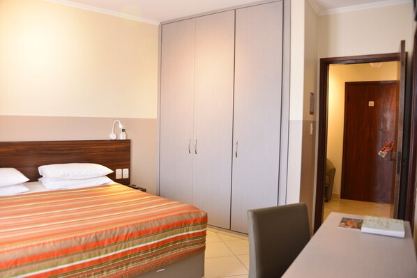 A hotel room with a bed, a desk, and a wardrobe.