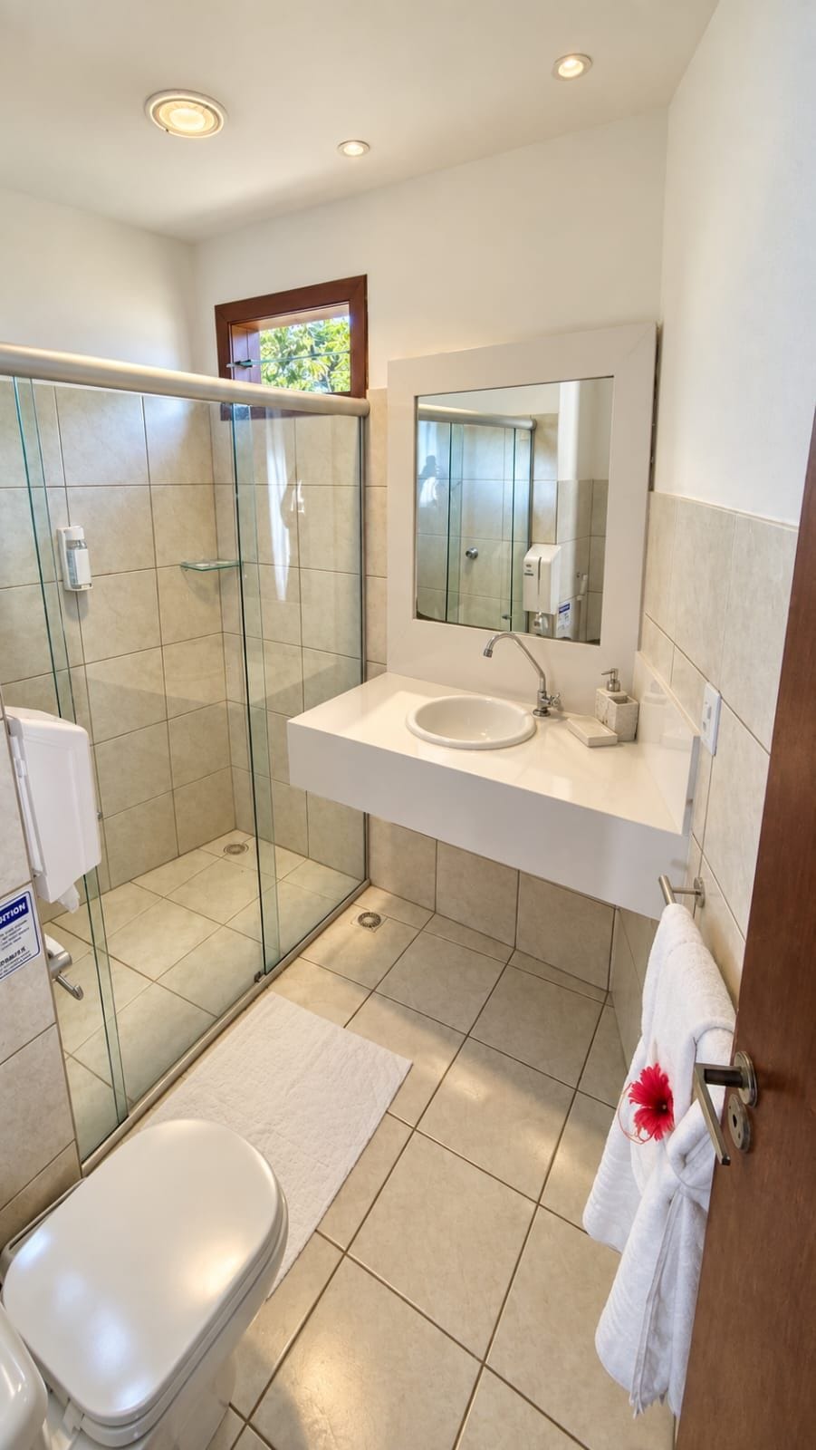A modern bathroom with a glass-enclosed shower, a white sink, and a toilet.