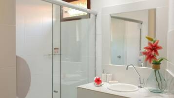A modern bathroom with a glass shower enclosure, a white sink, and a mirror above it.