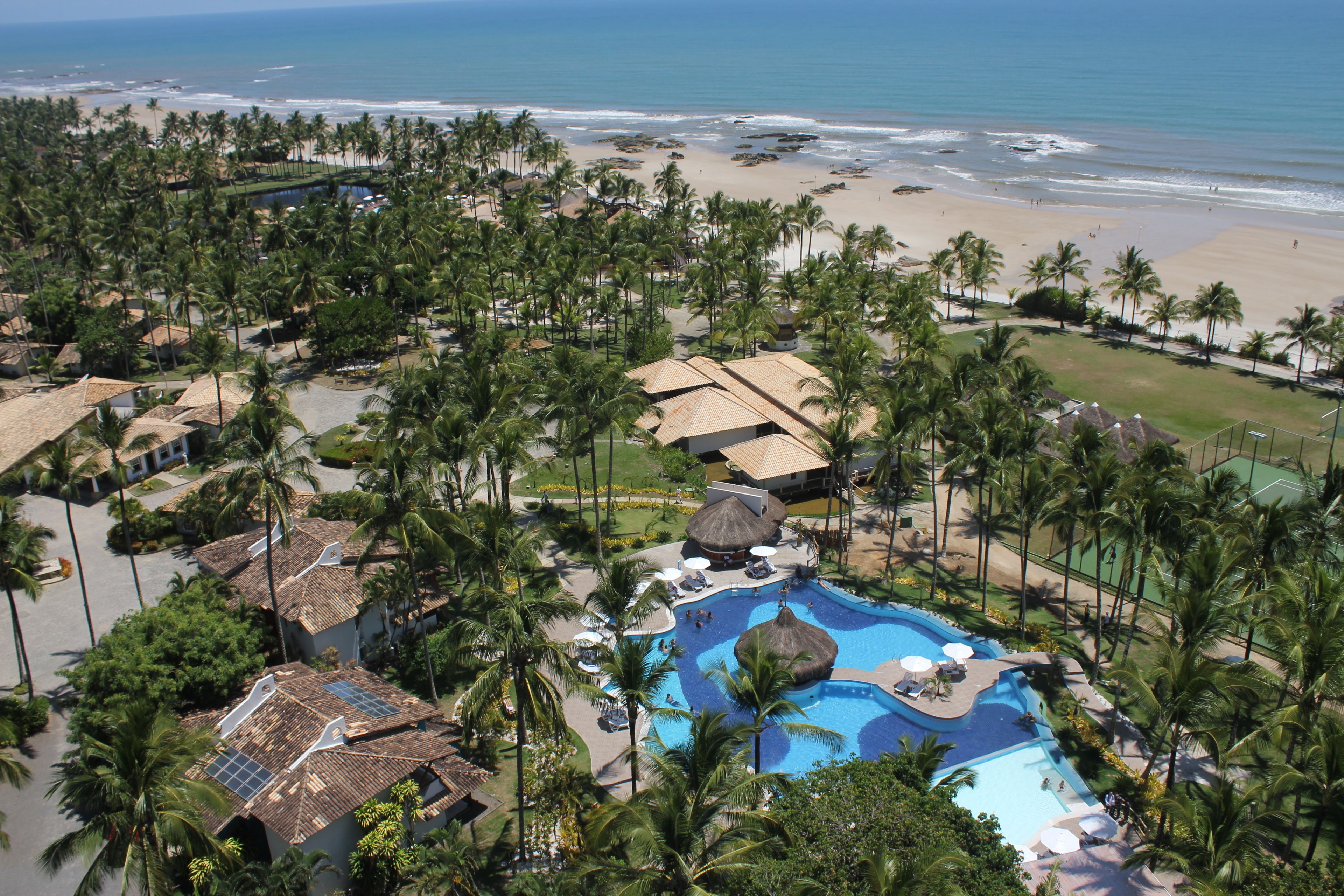 A resort with a large pool, palm trees, and a beach view.