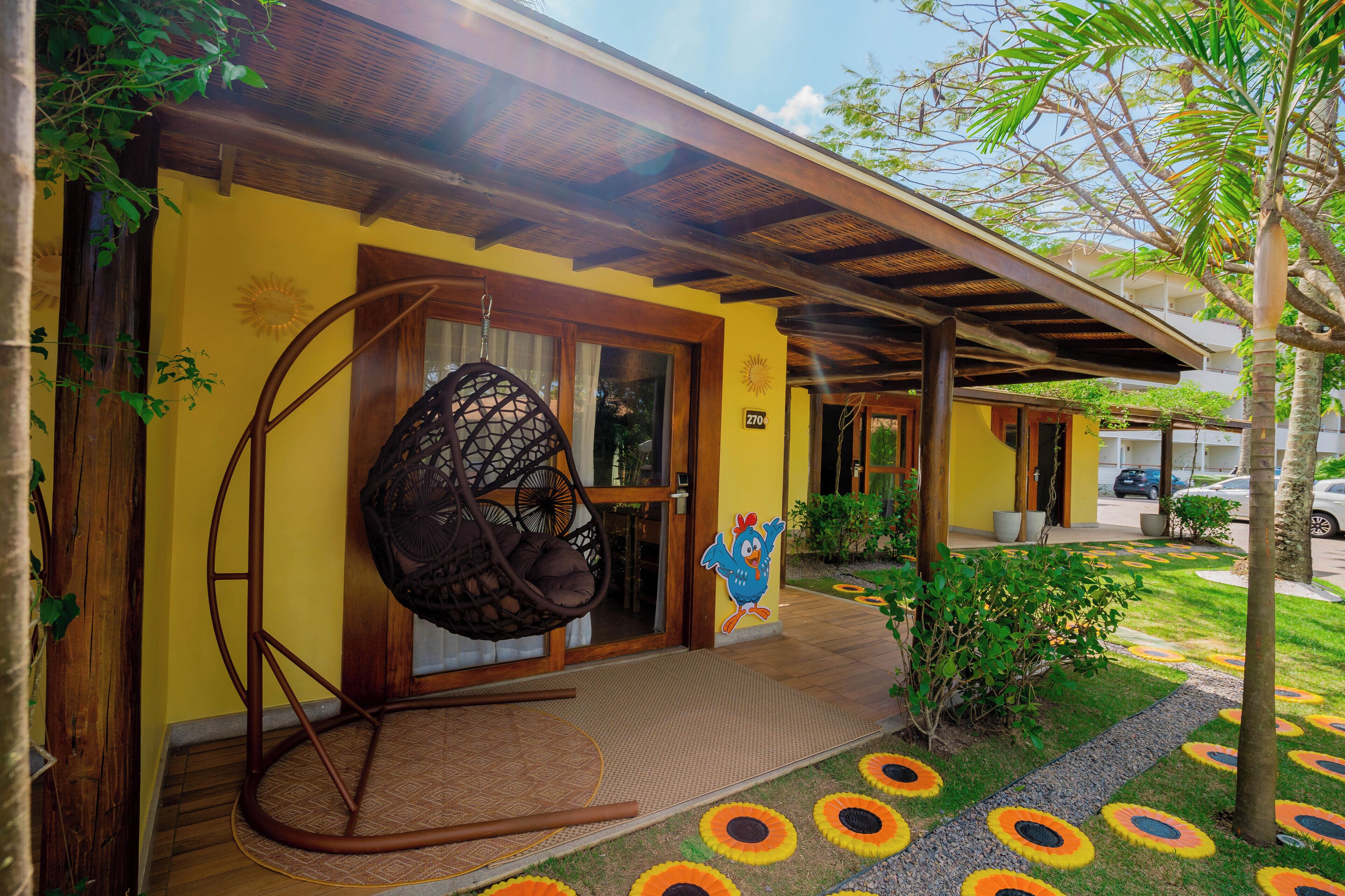 A building with a yellow facade, a wooden swing chair outside, and a number '270' on the door.