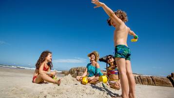 A group of people on a sandy beach with clear skies.