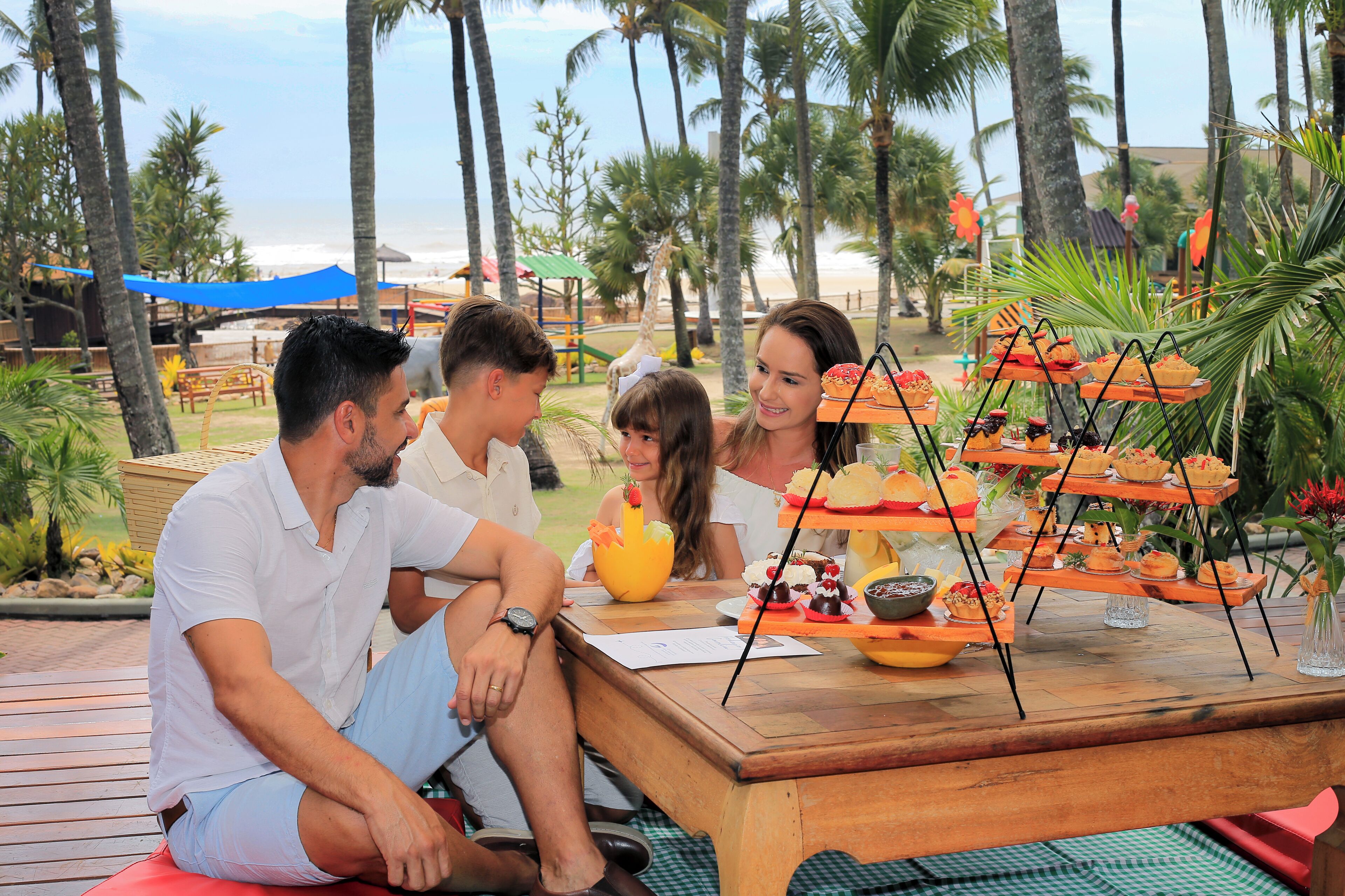 Un grupo de personas sentadas en una mesa al aire libre, con diversos platos de comida y una decoración central.