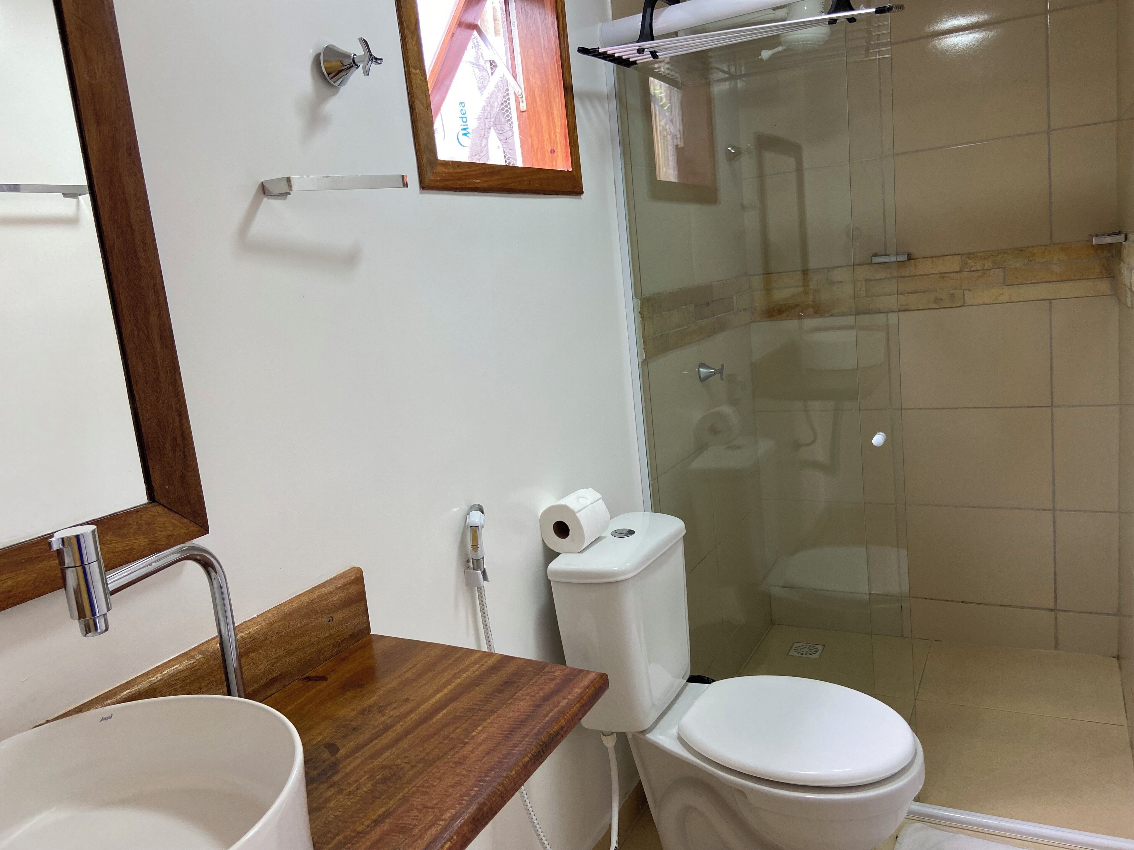 Een badkamer met een houten wastafelmeubel, een wastafel, een toilet en een douchecabine van glas.