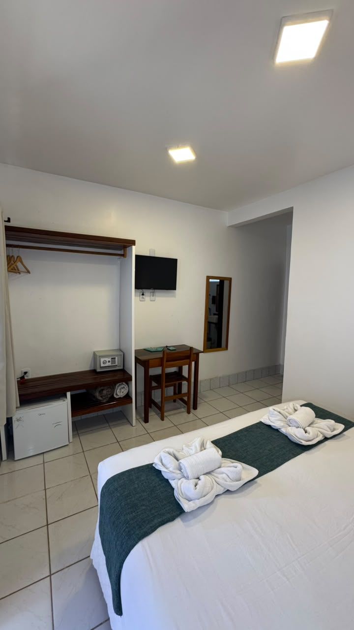 A hotel room with a bed, a desk, a television, and a wardrobe.