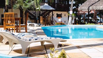 Una piscina al aire libre, sombrillas, sillones reclinables de piscina