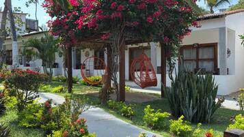 Un jardín con una silla colgante, un sendero y un edificio con un número en la puerta.