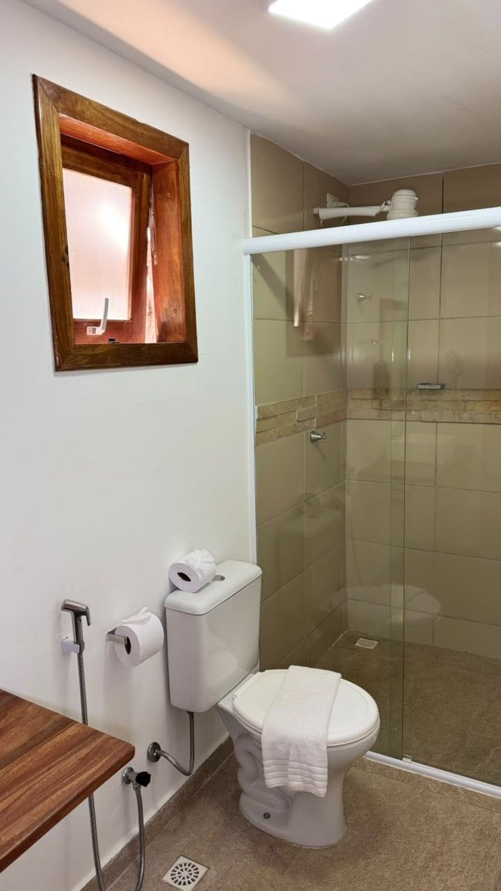 A bathroom with a toilet, shower, and a wooden-framed mirror.