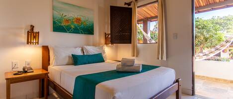A bedroom with a bed, bedside table, and a view of the outside.