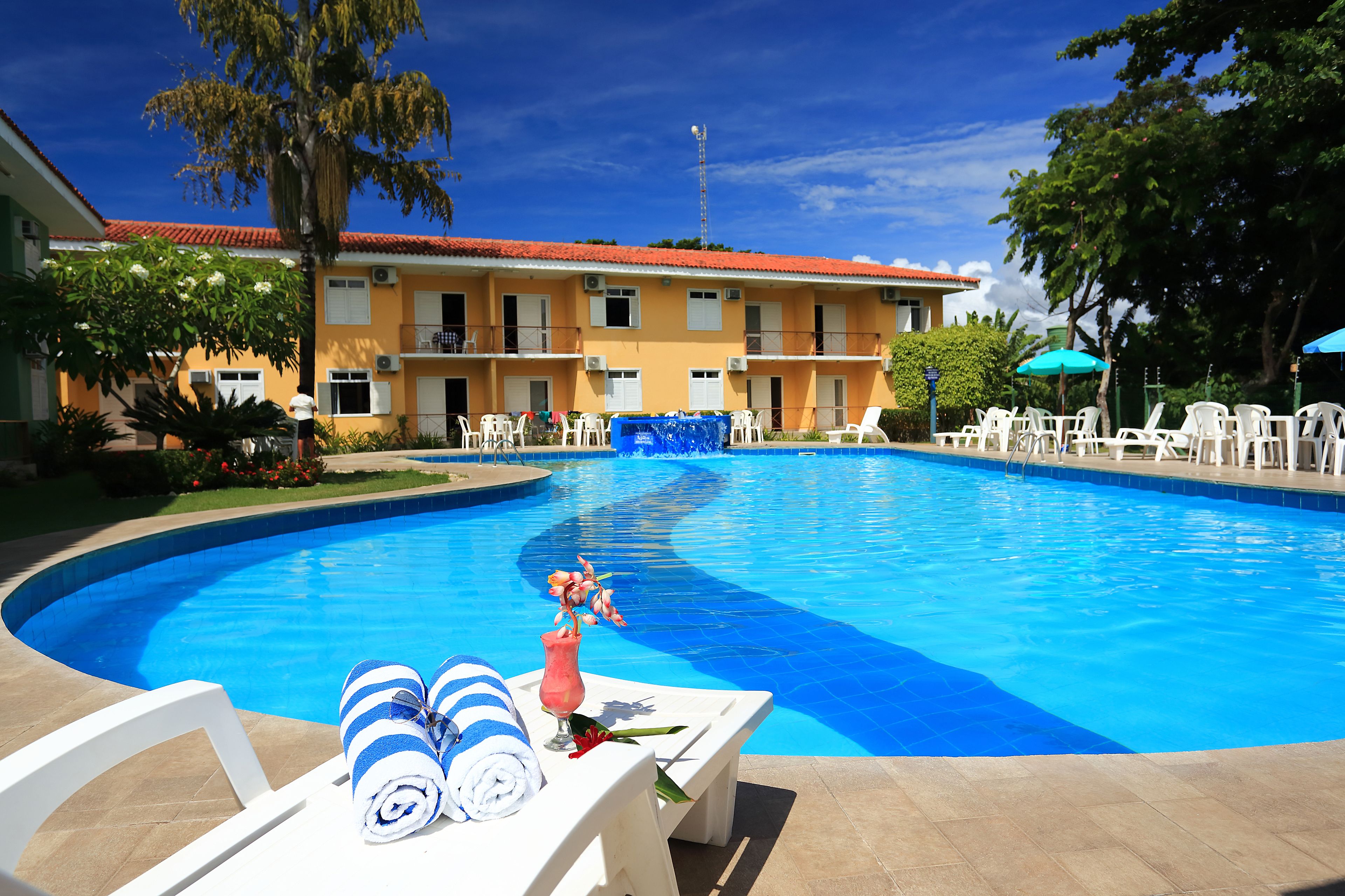 Una piscina al aire libre, sombrillas, sillones reclinables de piscina