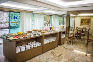 Ein reichhaltiges Buffet mit verschiedenen Speisen und eine Sitzgelegenheit mit Holzbänken und -stühlen.