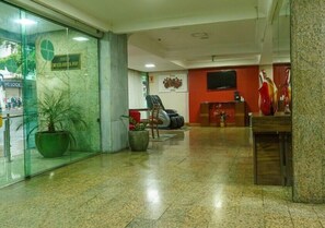 Eine Lobby mit Empfangstresen, Sitzgelegenheiten und einem großen Fenster mit Blick auf die Straße.