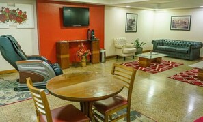 Uma sala de estar com televisão, lareira, sofá, mesa de centro e um espaço de jantar com cadeiras.