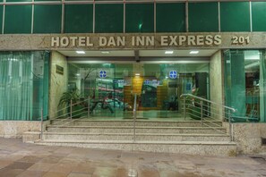 Der Eingang zum Hotel Dan Inn Express mit einer Marmorfassade, Glastüren und einer Metalltreppe zum Eingang.