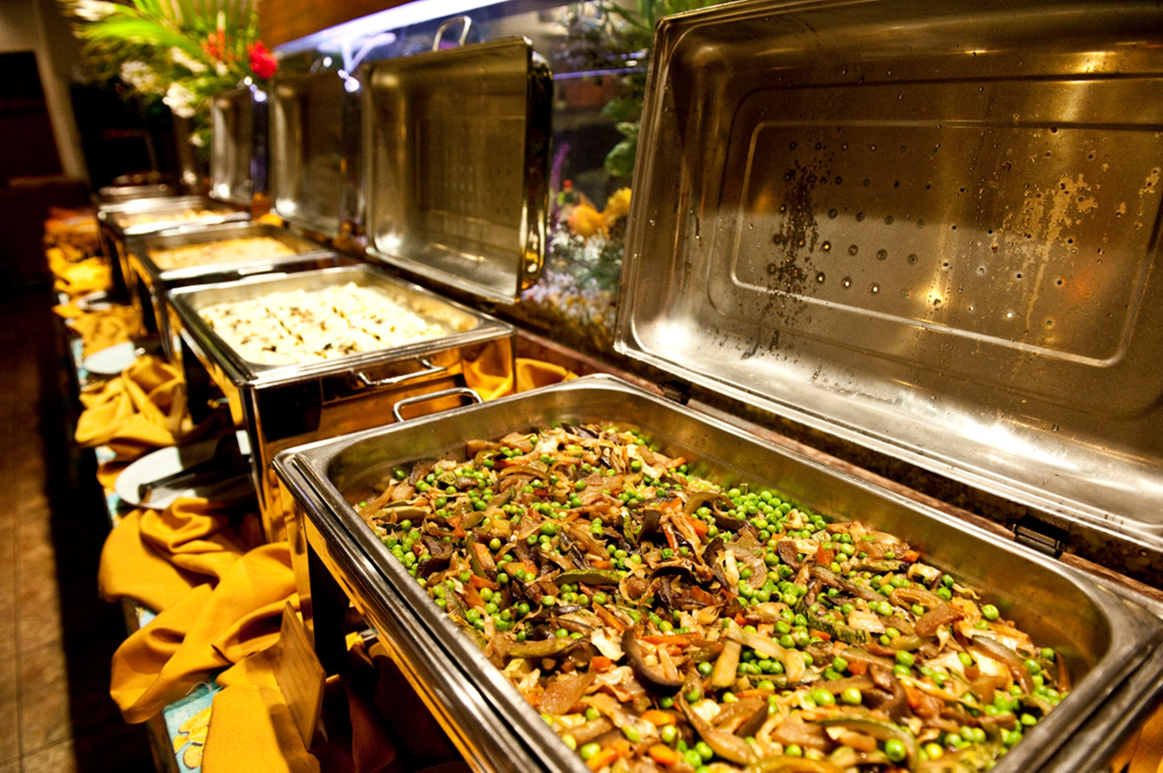 Un buffet proposant divers plats, notamment un grand récipient contenant un mélange de légumes et de viande.