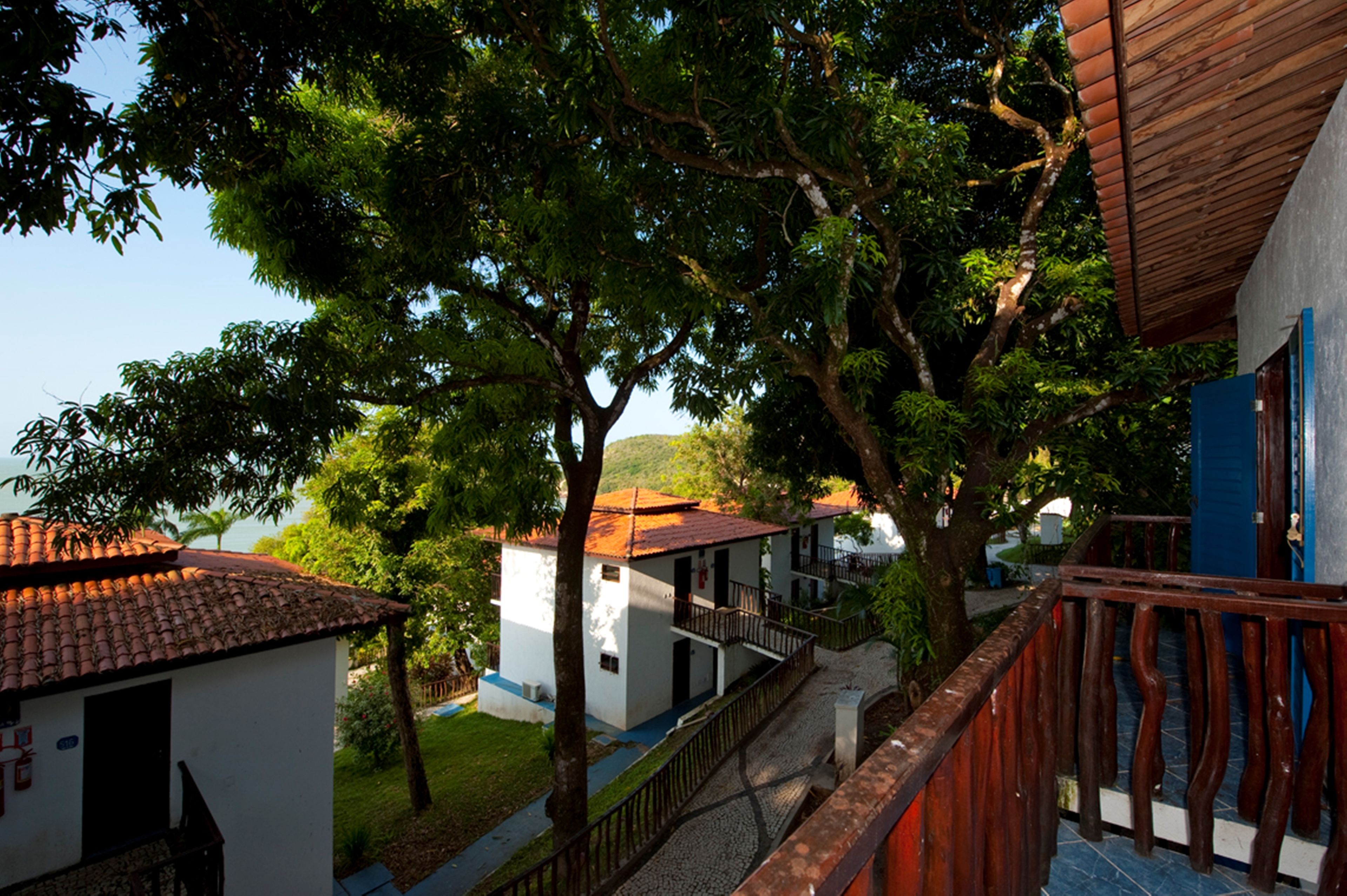 Vista de una zona residencial con casas, árboles y un balcón de madera.