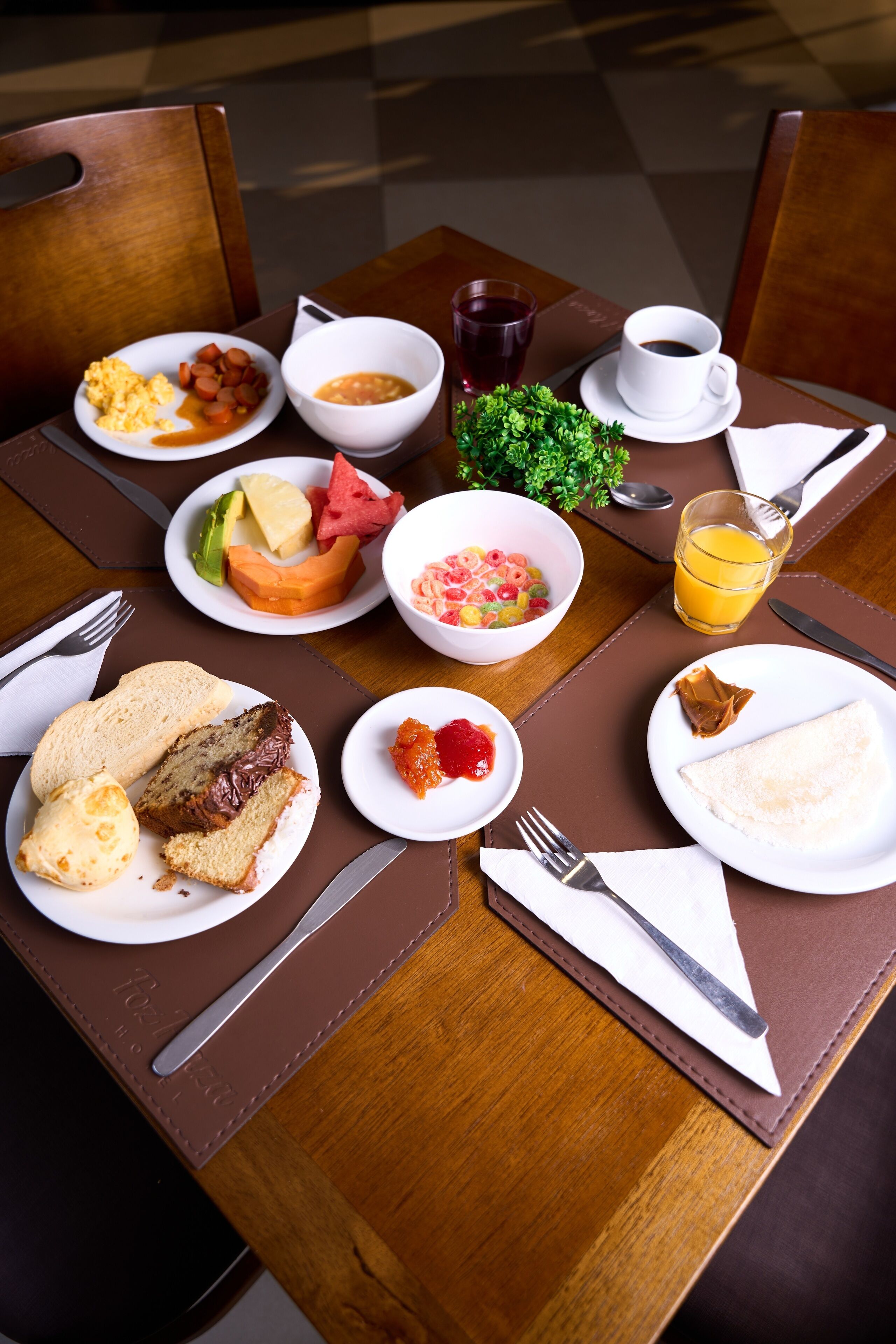 A breakfast table with plates of food, a cup of coffee, and a glass of orange juice.