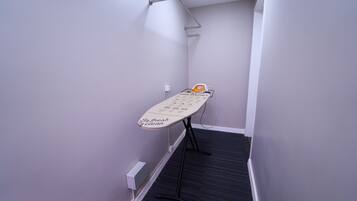 A narrow hallway with a wall-mounted ironing board and a towel rack.