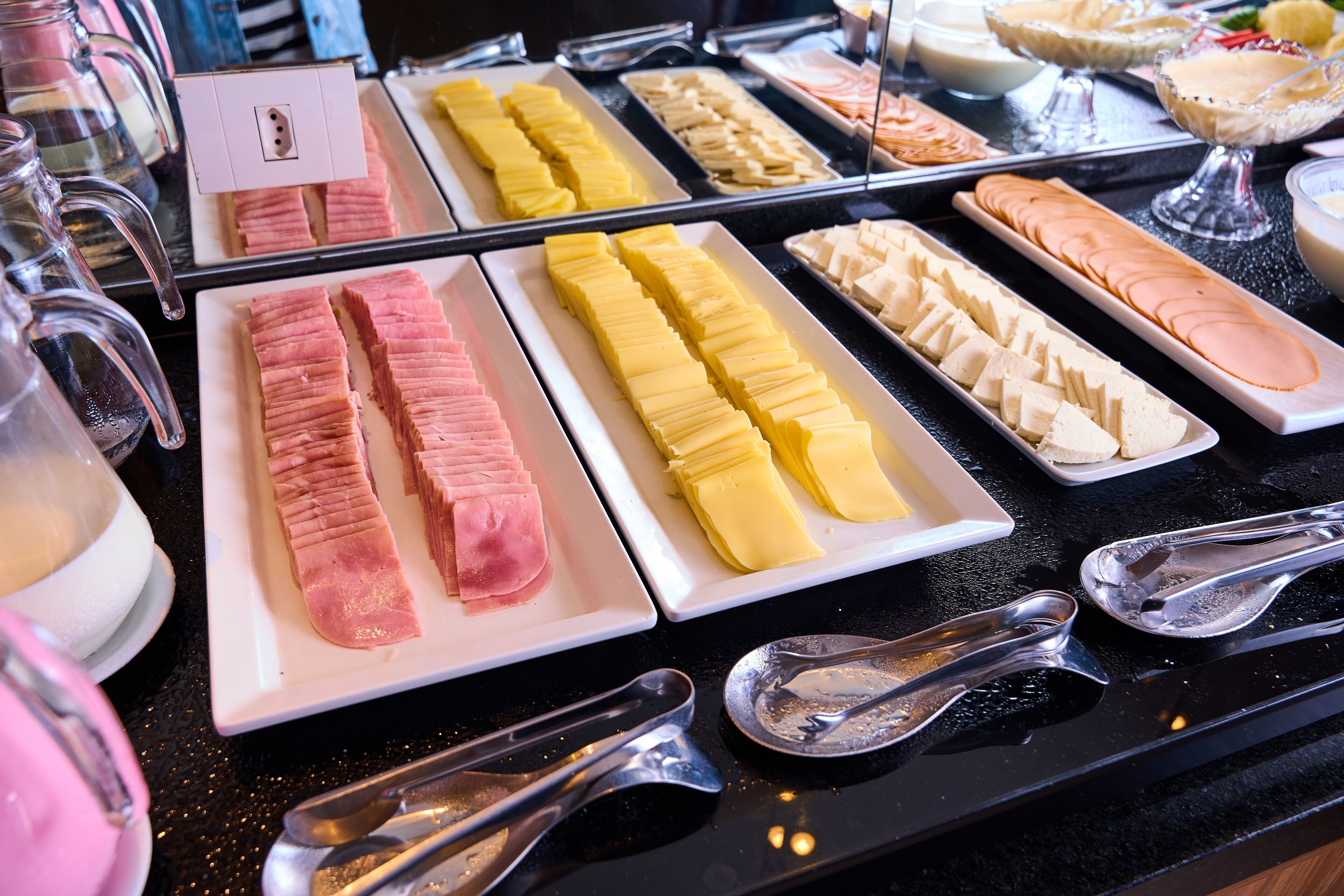 A buffet with various food items including meats and cheeses.