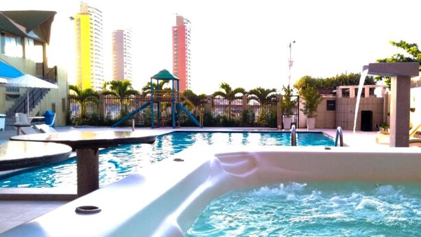 A swimming pool with a hot tub, lounge chairs, and a children's play area. - Golden Beach Hotel (Fortaleza)
