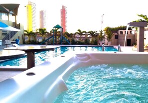 Piscina com hidromassagem, espreguiçadeiras e área de recreação infantil.