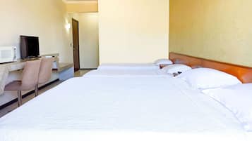 Quarto de hotel com duas camas, uma escrivaninha com computador e uma cadeira.