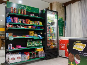 A vending machine stocked with snacks and beverages, a refrigerated display case, and a promotional stand for Frosty ice cream. - Golden Beach Hotel (Fortaleza)