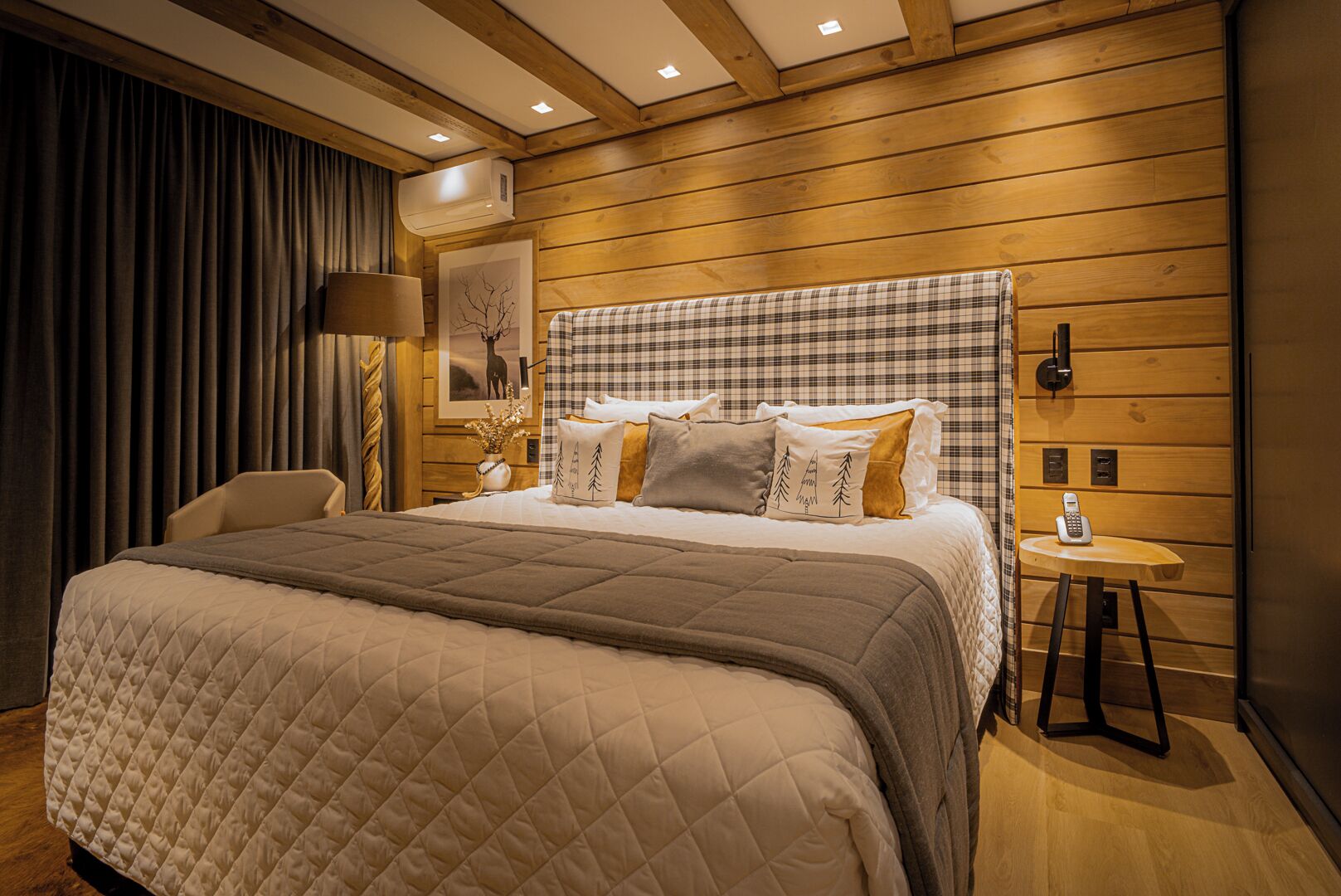 A modern hotel room with a large bed, a bedside table with a lamp, and a telephone.