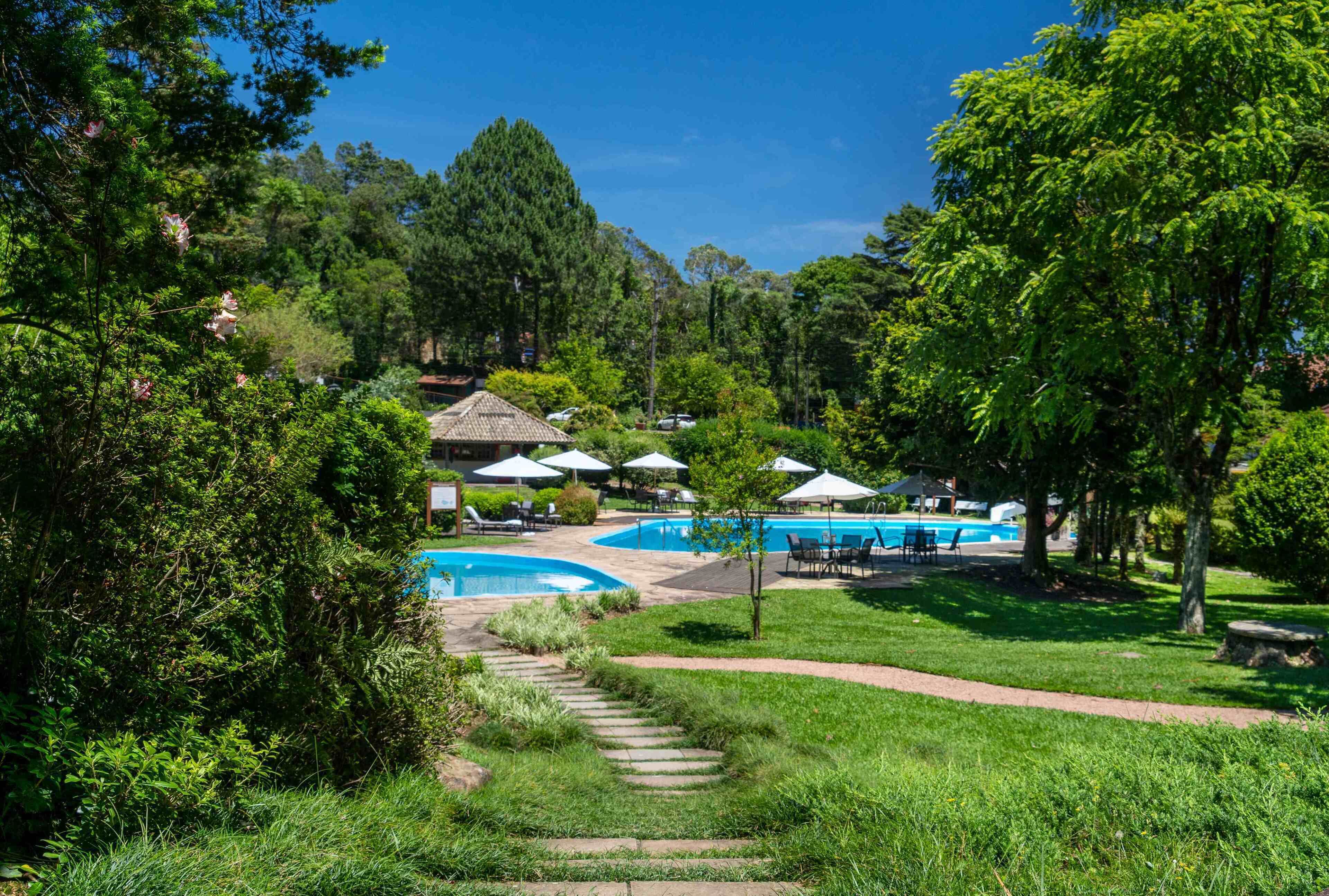 Un resort con múltiples piscinas, zonas de descanso y un jardín bien cuidado.