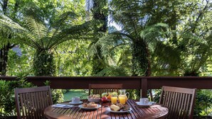 A wooden table set with breakfast items, surrounded by lush greenery. - Hotel Alpestre (Gramado)