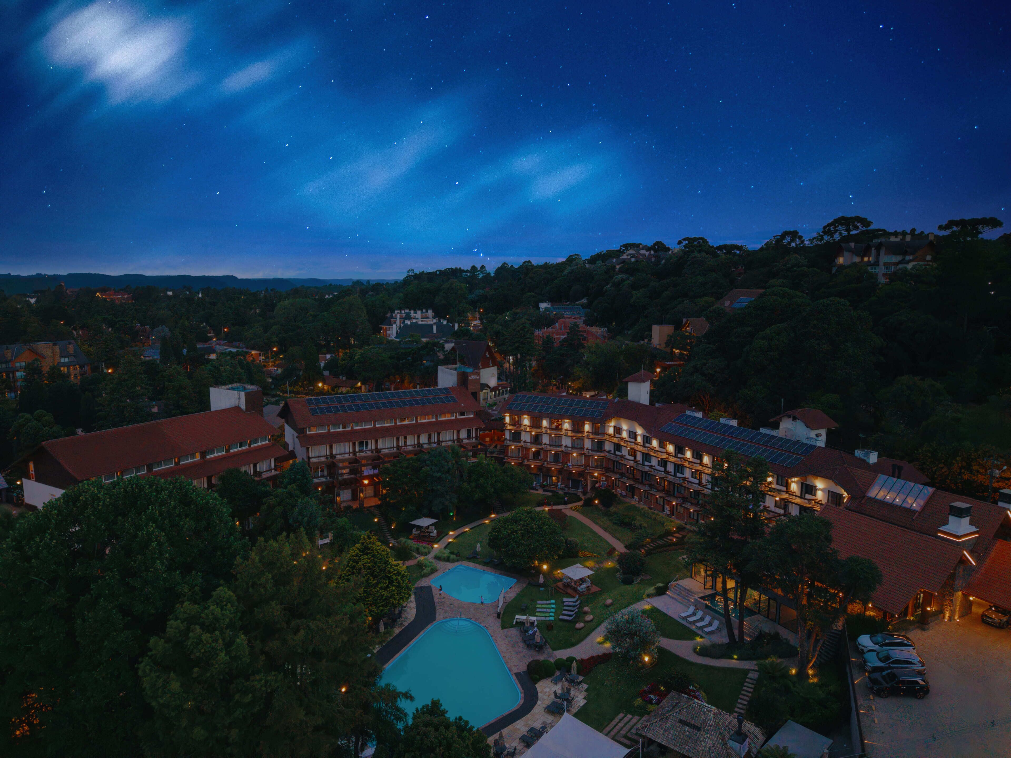 A hotel with a swimming pool, solar panels, and a starry night sky.