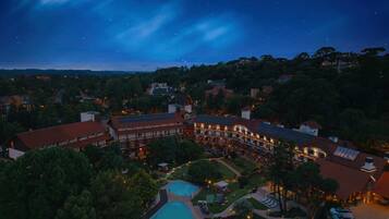 A hotel with a swimming pool, solar panels, and a starry night sky.