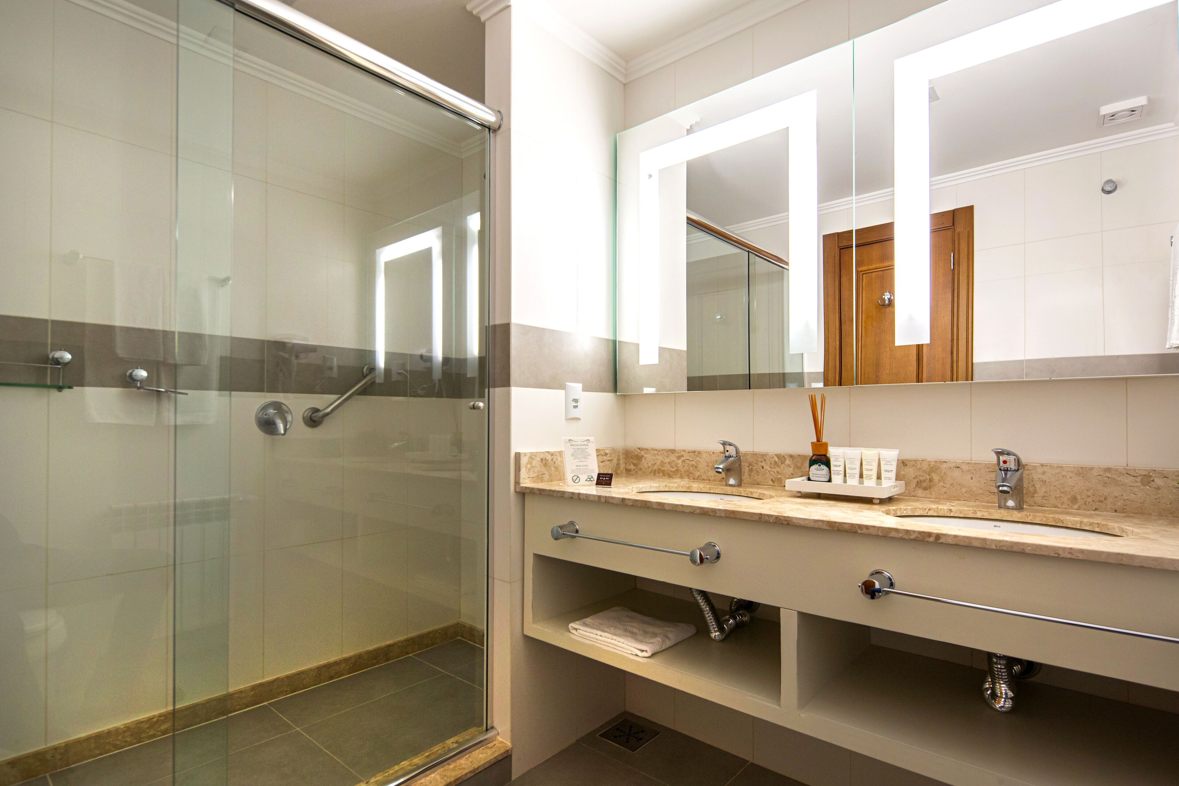 A modern bathroom with a glass-enclosed shower, a large mirror, and a vanity with a sink and towel rack.