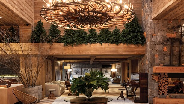 A spacious lobby with a high ceiling, a large wooden chandelier, and a stone fireplace. - Hotel Alpestre (Gramado)