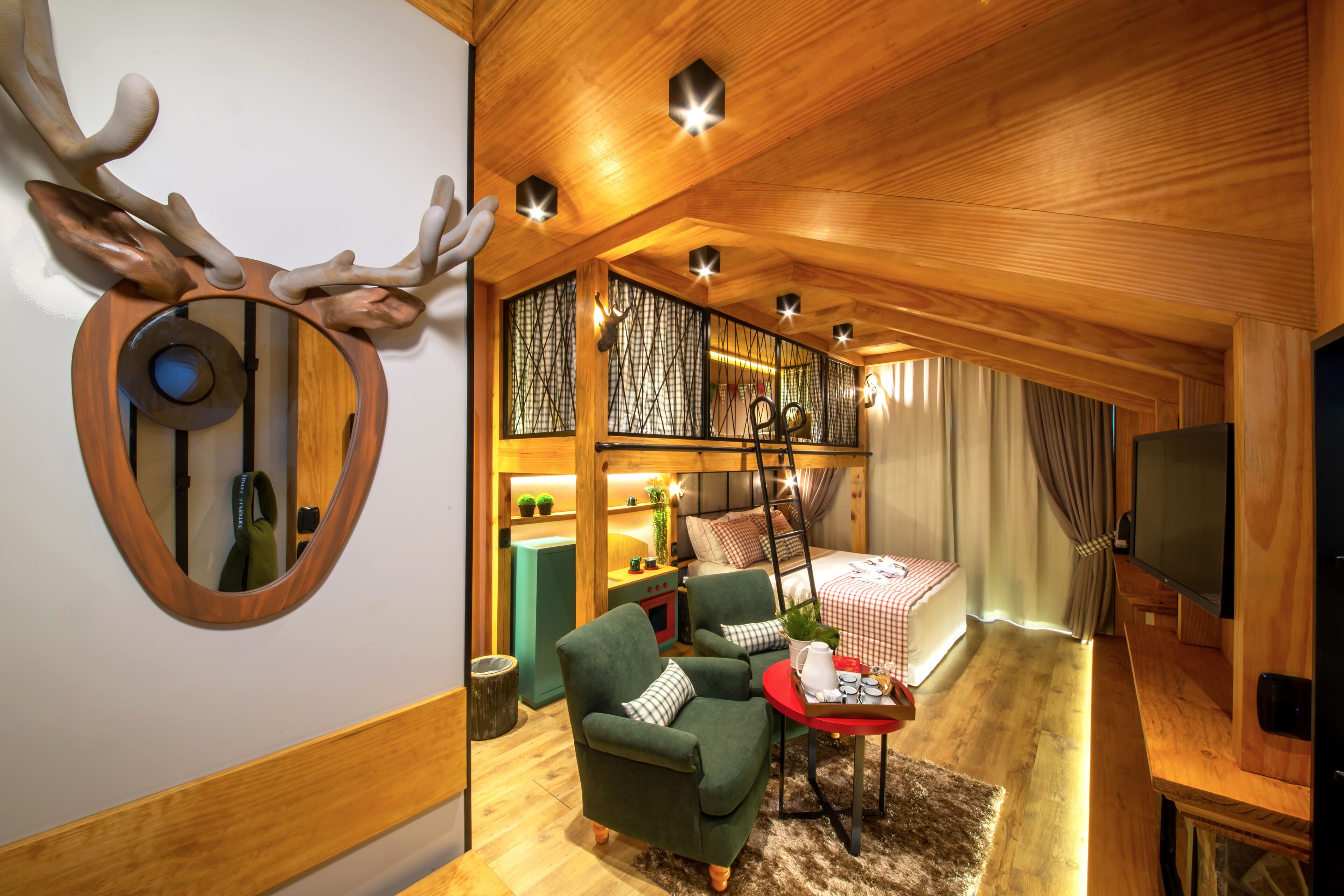 A cozy room with a bed, a green armchair, a small table, and a TV.