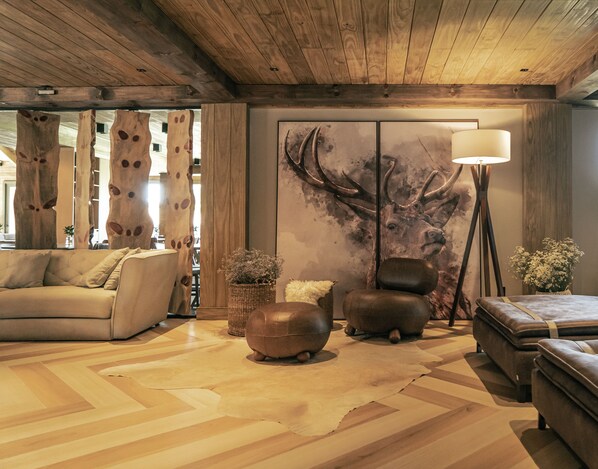 A cozy living room with a sofa, ottoman, and a large deer wall art piece.
