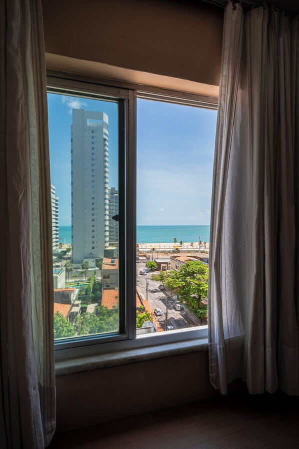 Una habitación con un ventanal grande que da a la playa y edificios altos.