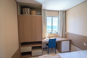 Habitación de hotel con cama, escritorio con silla, un refrigerador pequeño y un armario.