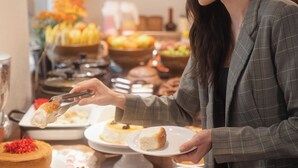 Un bufé con distintos alimentos y una persona sirviéndose.