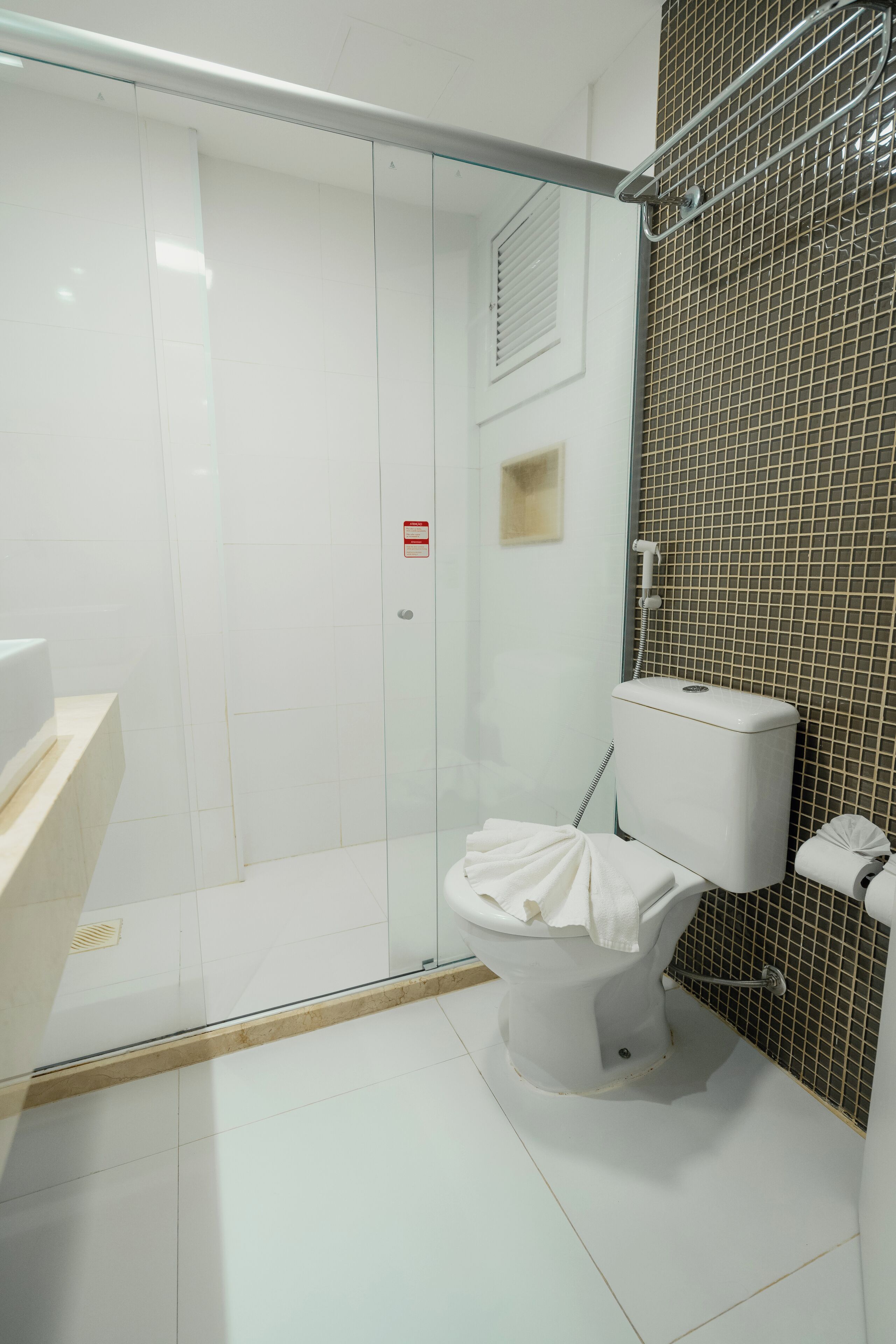 A modern bathroom with a glass shower enclosure, a white toilet, and a sink with a beige countertop.