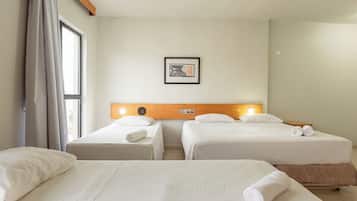 Una habitación de hotel con dos camas individuales, un cabecero de madera, un cuadro en la pared y una ventana con cortinas.
