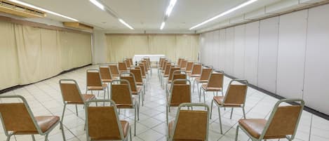 A conference room with rows of metal-framed chairs and a long table at the front.