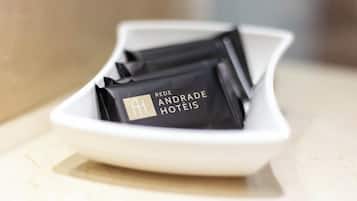 Un plato blanco que contiene etiquetas negras con el nombre del hotel: 'REDE ANDRADE HOTÉIS'.
