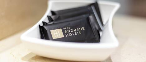 Un plato blanco que contiene etiquetas negras con el nombre del hotel: 'REDE ANDRADE HOTÉIS'.