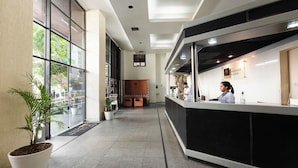 Un espace d’accueil d’hôtel comprenant un comptoir, un bureau d’accueil et une grande fenêtre.