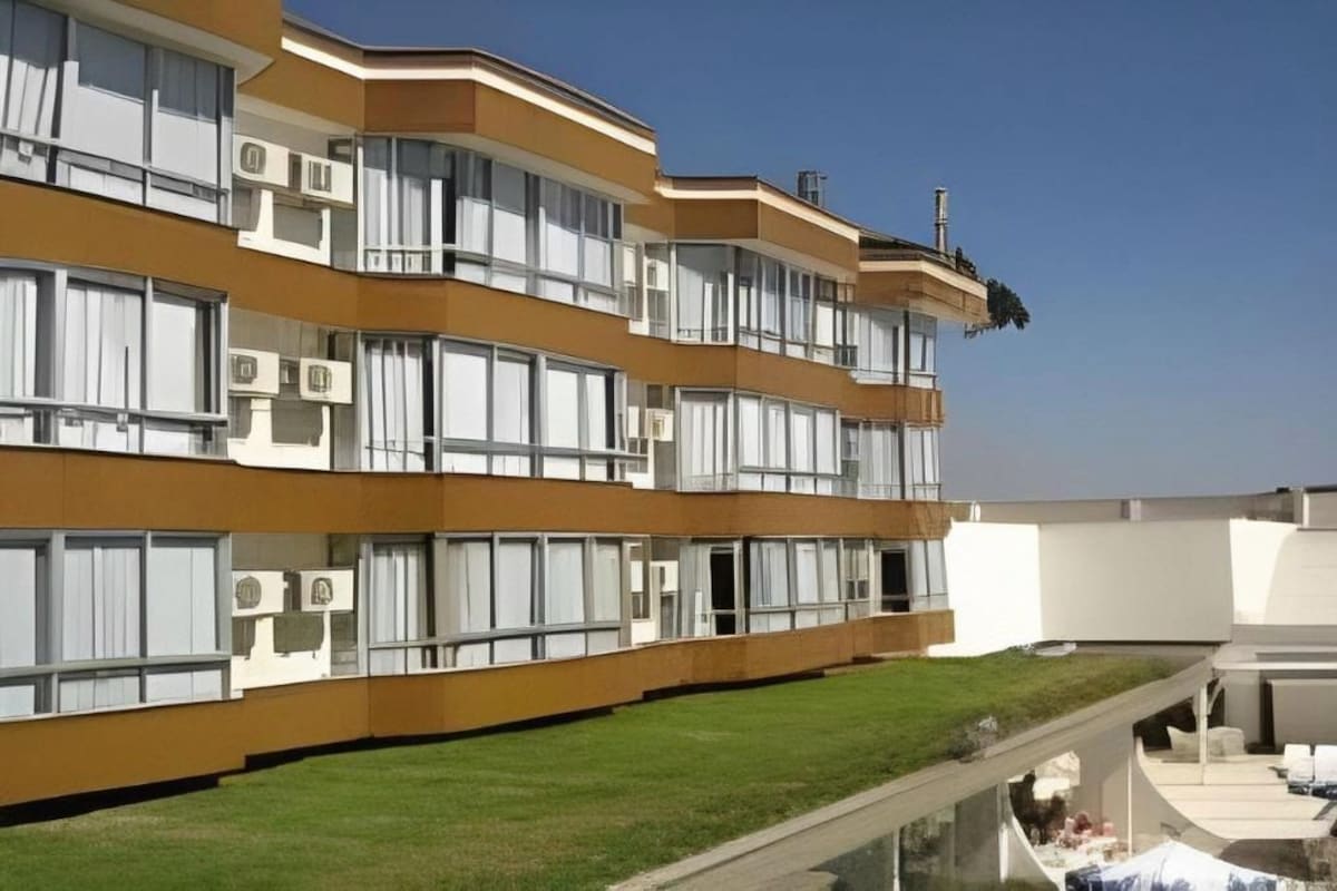 Un hotel de varios pisos con balcones, unidades de aire acondicionado y una terraza en la azotea.