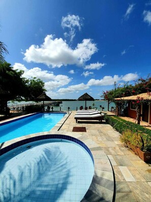 A swimming pool with lounge chairs and a view of the sea. - Pousada Peixe Galo (Galinhos)