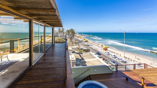 Una terraza de madera con vista a la playa y al océano.