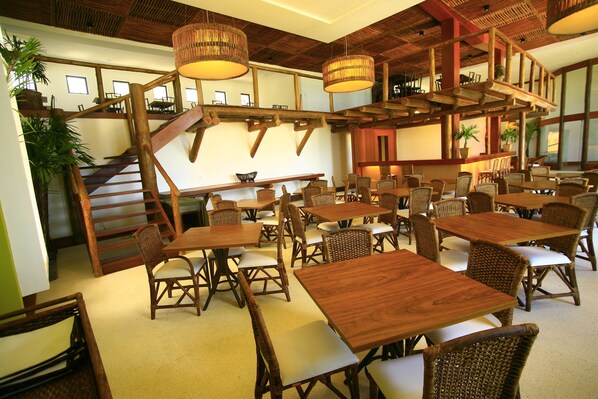 A restaurant with wooden tables and chairs, a staircase, and hanging wicker lamps. - Porto Suites Natal Hotel (Natal)